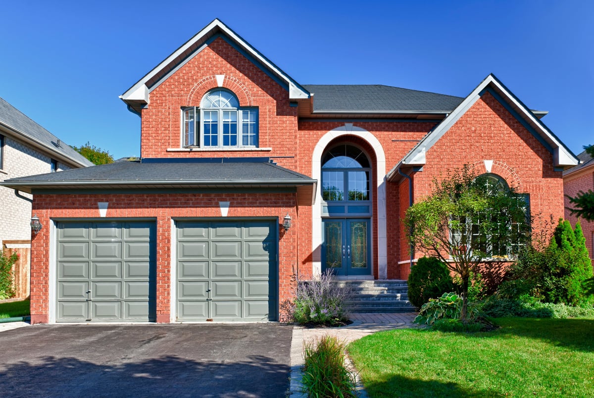 Two-story brick home in suburbs with two car garage, 1970s traditional style