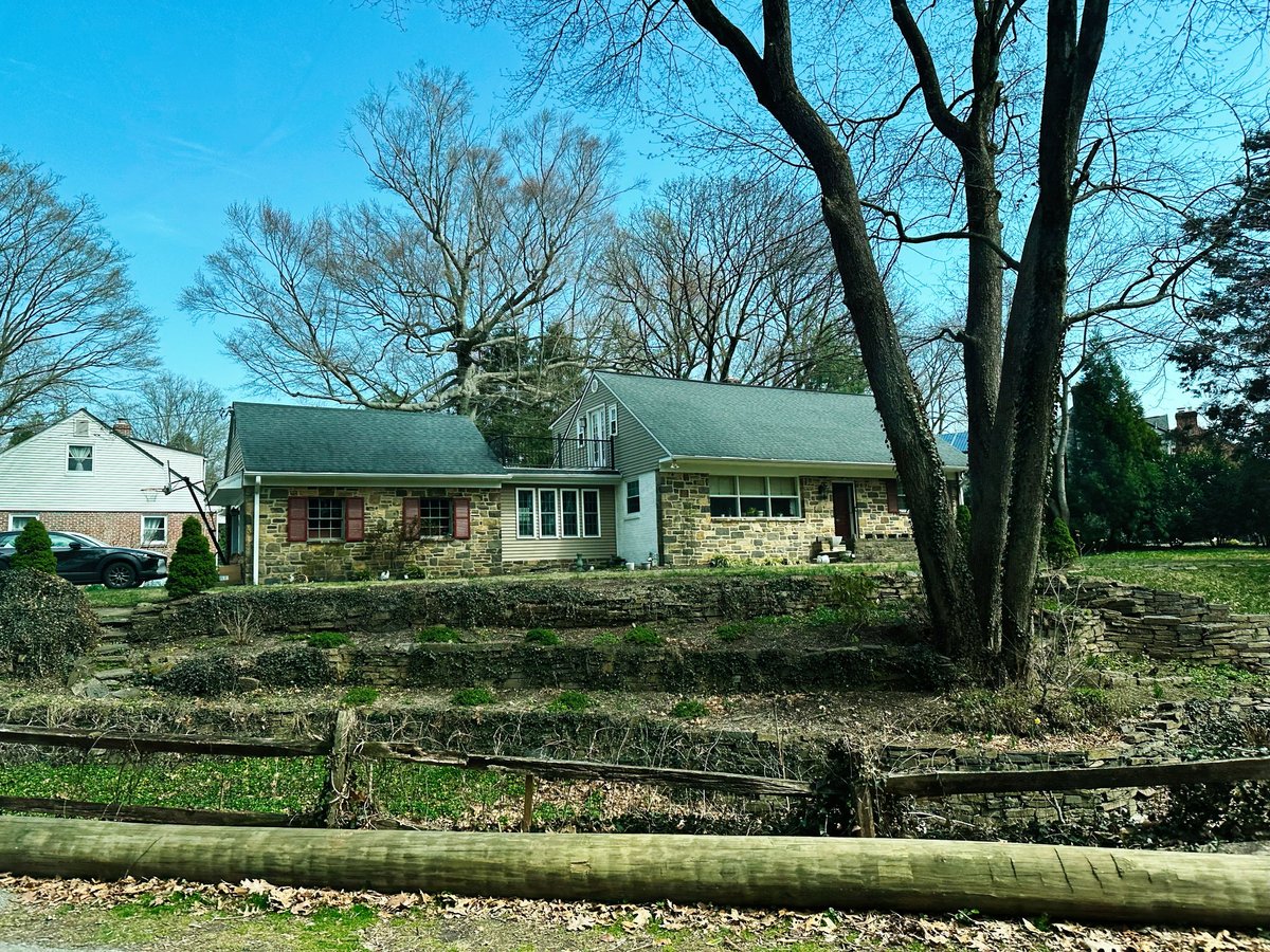 Stone house with landscaped yard and trees, bright sunny day in Pennsylvania