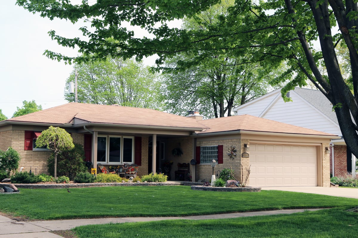 Typical 1960s era home with attached garage and well landscaped street
